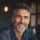 Homme souriant avec barbe grise en chemise.